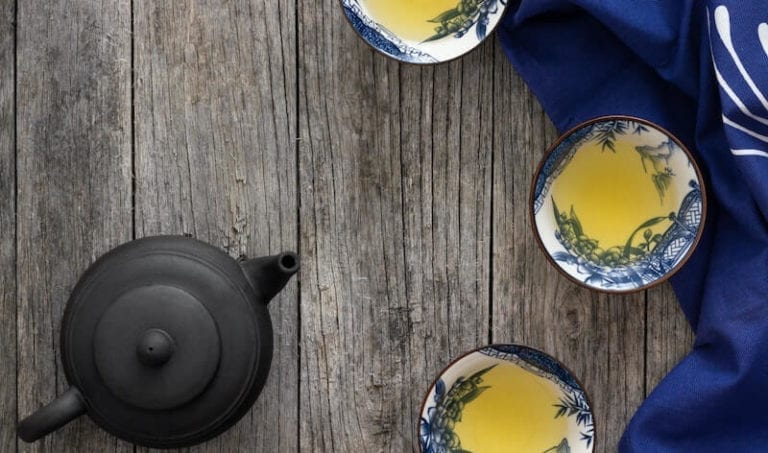 Photo of three cups of tea and a teapot