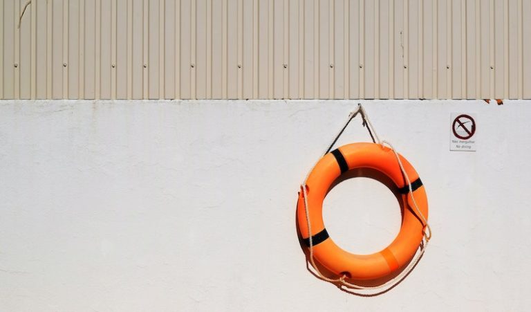 An orange emergency life buoy hanging on a wall.