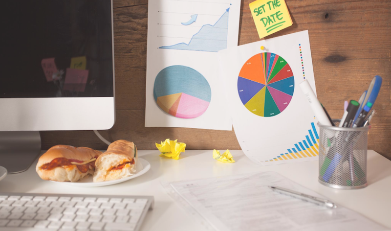 Papers on a desk with colourful pie charts and graphs